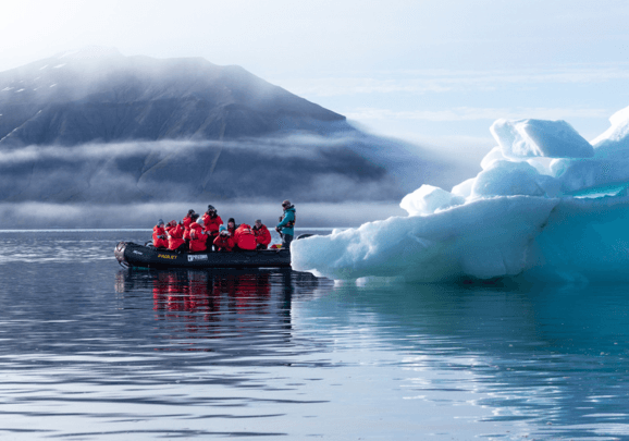 Schlauchboot das in einem Fjord auf Spitzbergen um eine Eisscholle fährt